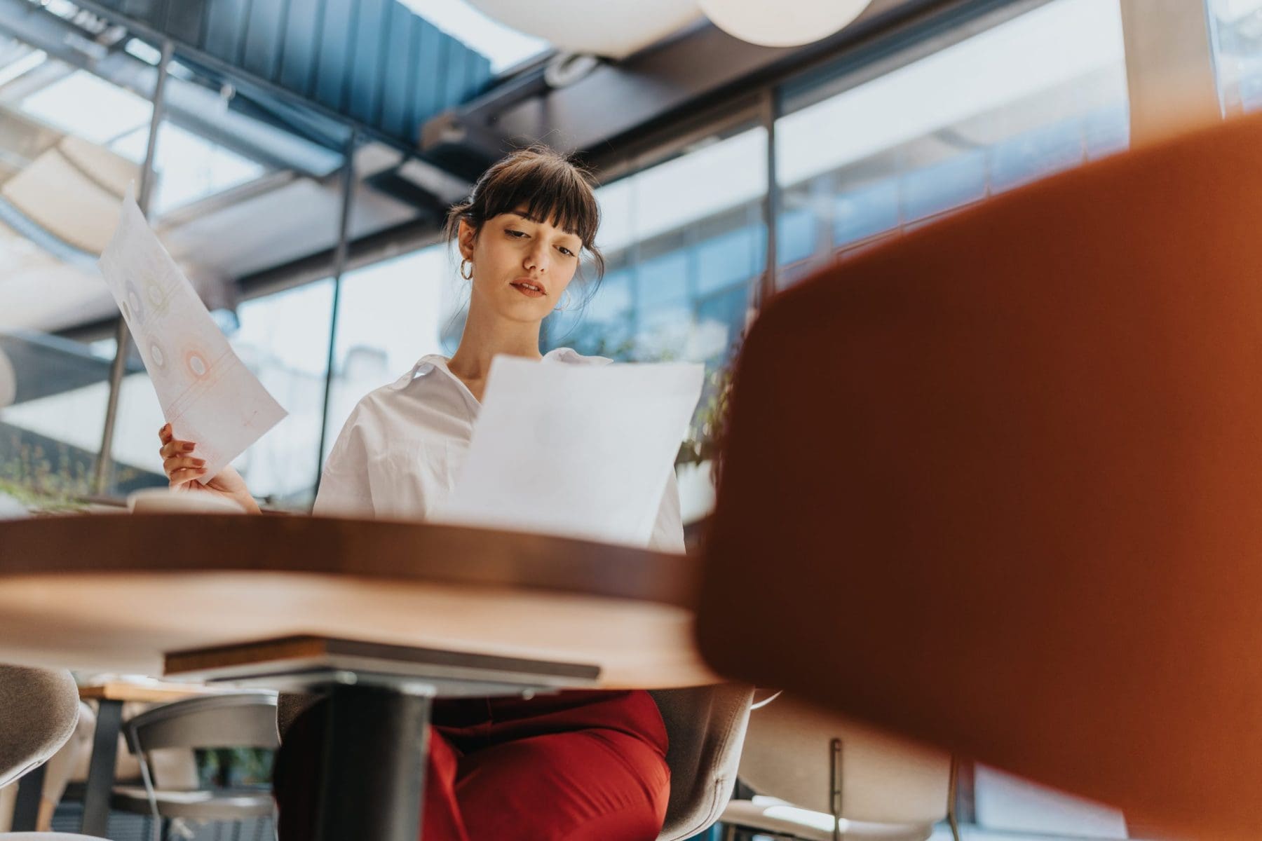 A young businesswoman examining documents while seated in a contemporary office,