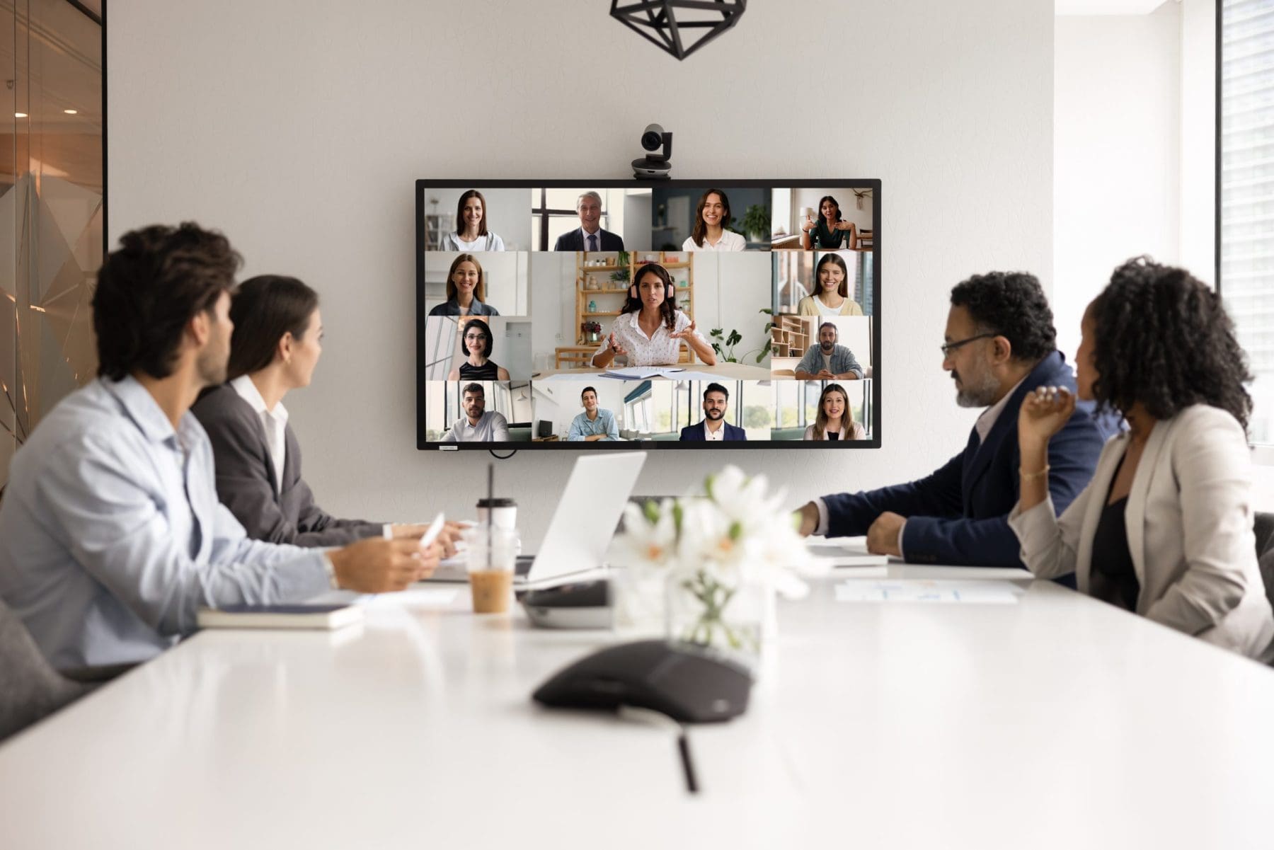 Diverse multiracial team collaborate during hybrid online and in person meeting.