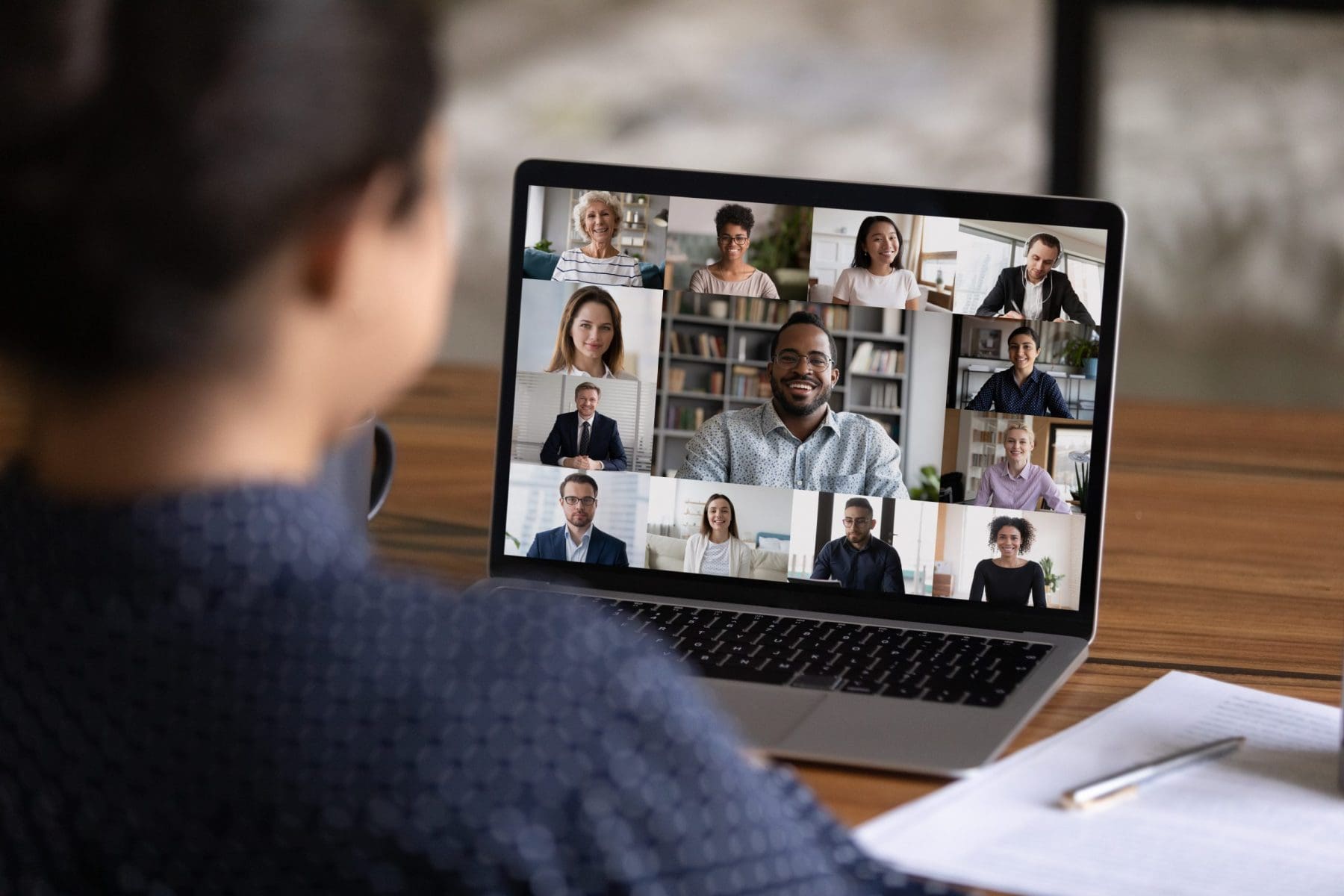 Over shoulder view of female worker on virtual conference with colleagues.