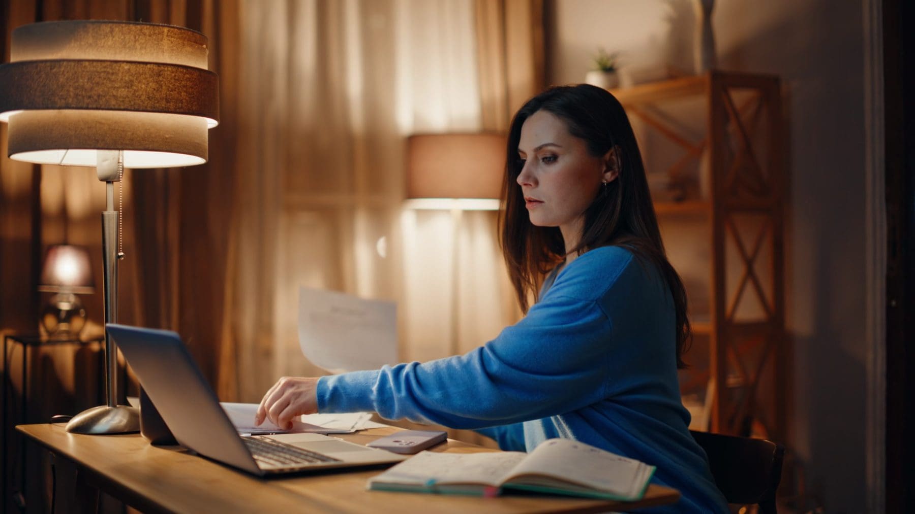 Stressed remote worker reading documents at dark workspace closeup.