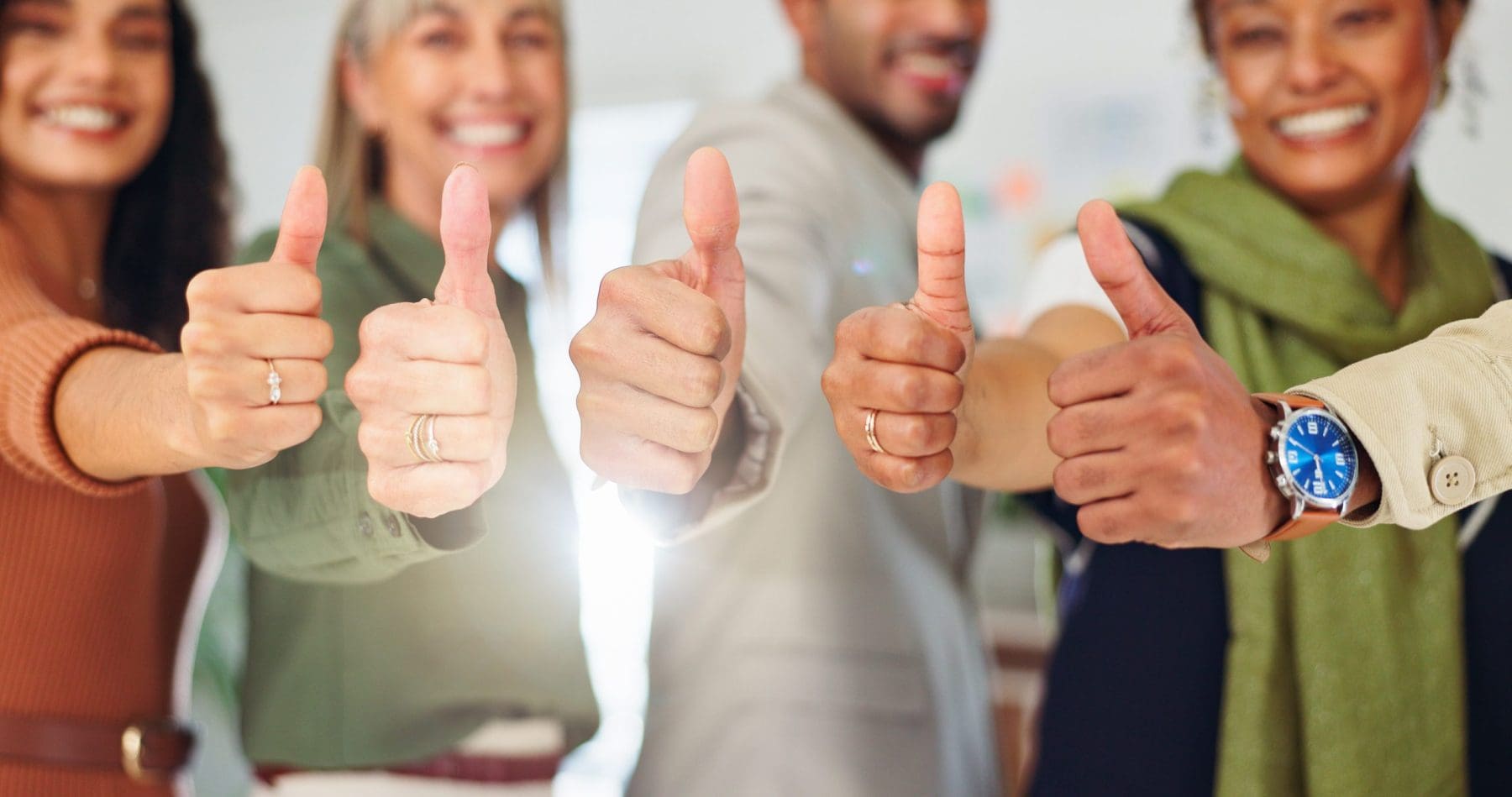 A group extends thumbs up in unison, showing enthusiasm and unity. The gesture highlights a positive and inclusive team culture.