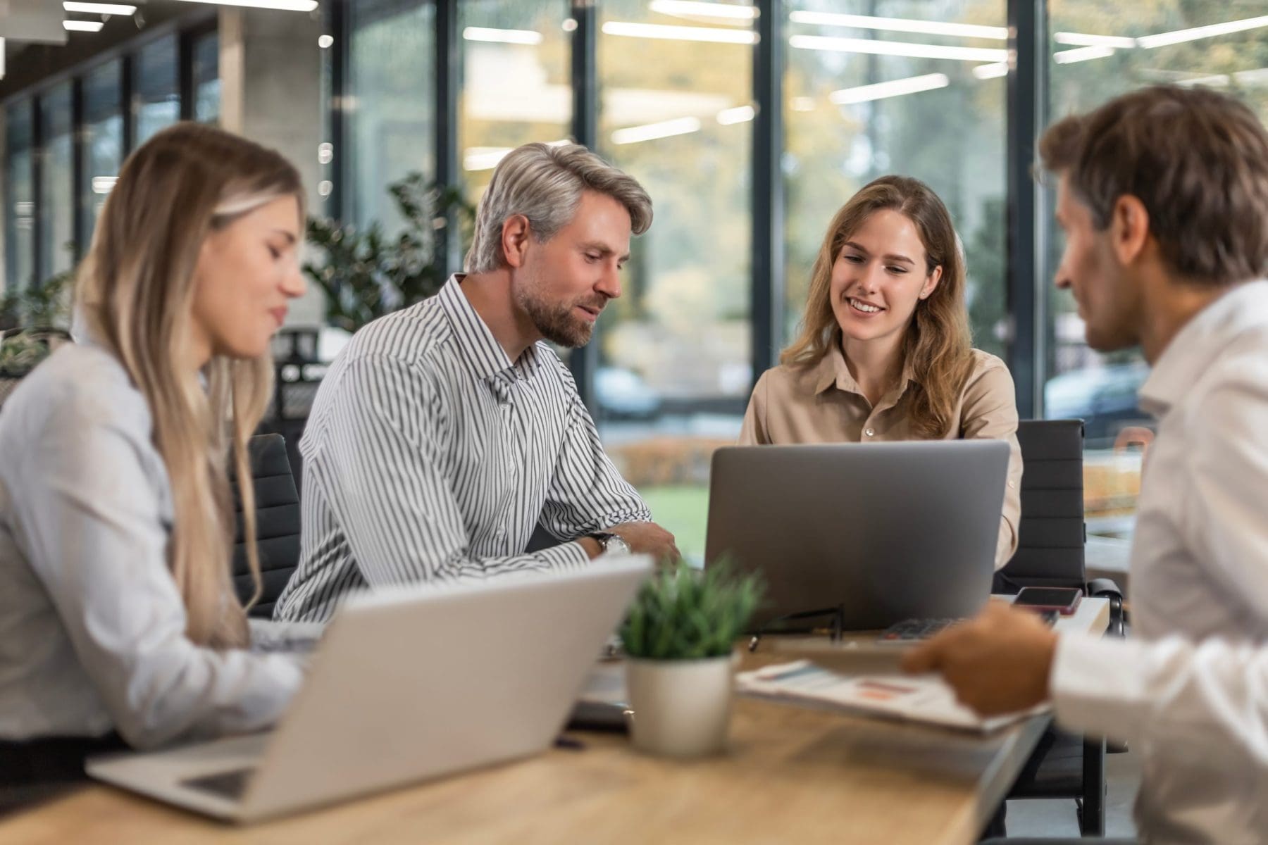 Two colleagues review a laptop together, exchanging smiles in a collaborative moment. They appear engaged and aligned as they work side by side.