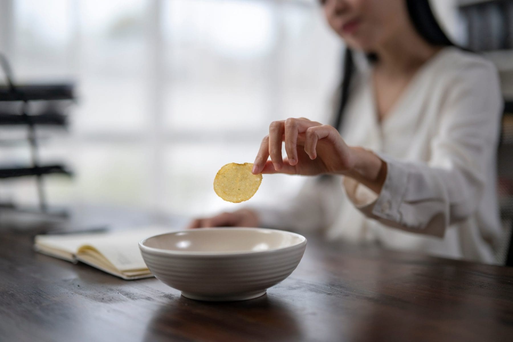 Businesswoman taking a potato chip from a bowl.