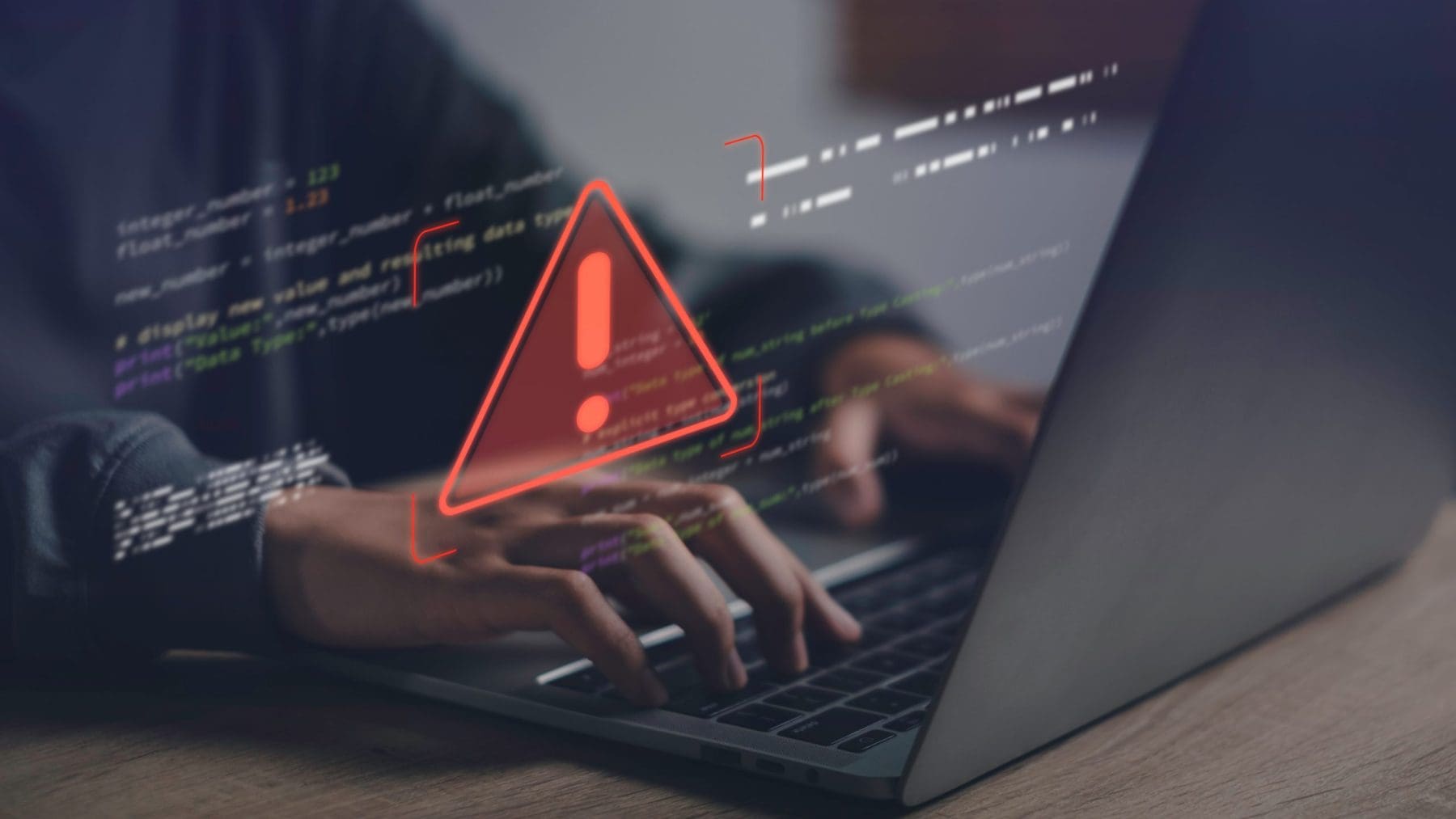 Close-up of hands typing on laptop with warning error icon and code overlay,.