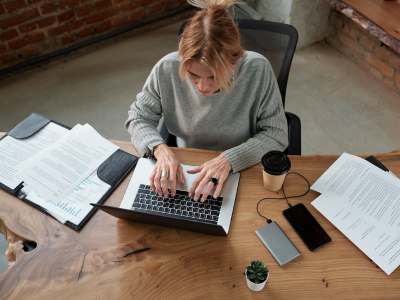 Top view of woman working on laptop on desk.