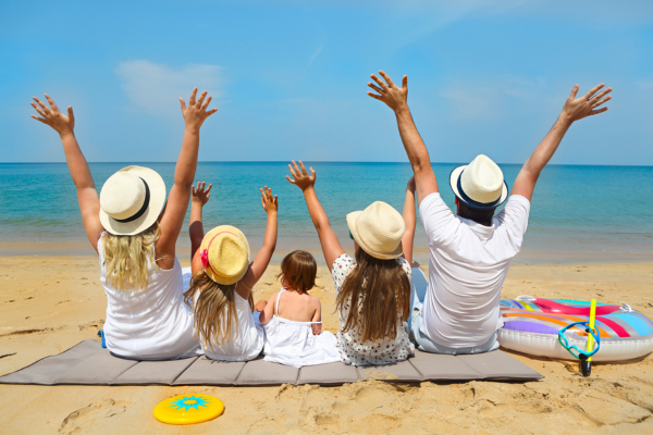 View of family sitting on beach during summer time.
