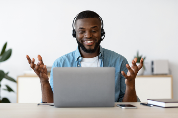 Man smiling while using headphones and engaging in online meeting.