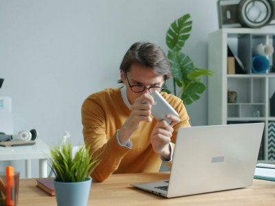 Man working from home while using laptop and phone.