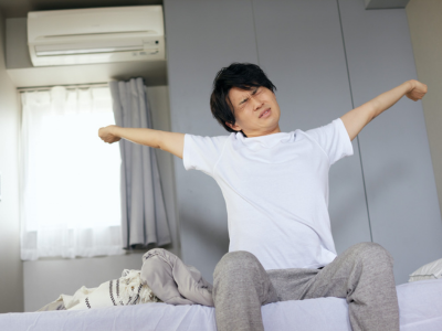 Man sitting on bed and stretching.