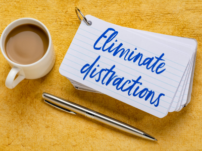 Cup of coffee and note pad with word eliminate distractions.
