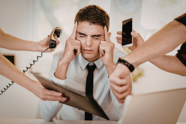 Man closing his eyes and trying to ignore calls, tablet and phone,