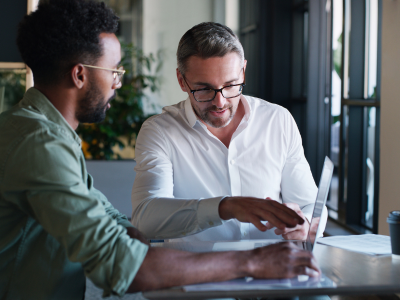 Two man in a meeting looking at laptop.